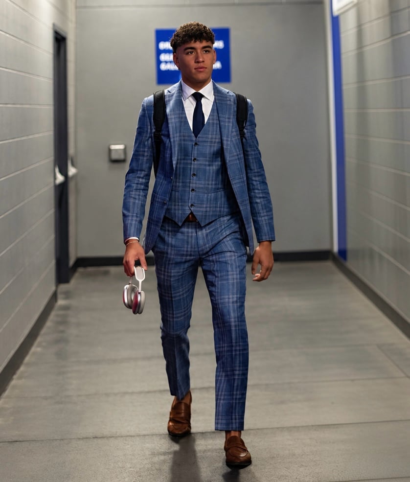 Young man in blue plaid three-piece suit walking through a modern hallway holding a helmet